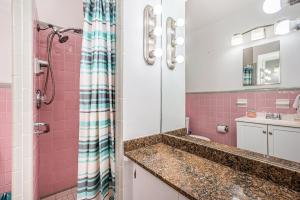 uma casa de banho com um lavatório e um chuveiro com azulejos cor-de-rosa em Blue Water Beachside villa 3 em Clearwater Beach