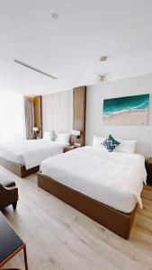 two beds in a hotel room with white walls at Panorama Beachfront Nha Trang in Nha Trang