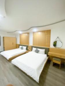2 Betten in einem großen Zimmer mit einem Schreibtisch in der Unterkunft Son Ca Motel in Hue