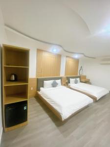 ein Schlafzimmer mit 2 Betten und einem Bücherregal in der Unterkunft Son Ca Motel in Hue