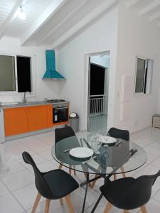 uma sala de estar com uma mesa de vidro e cadeiras em Maison dans les hauteurs em Le Gosier