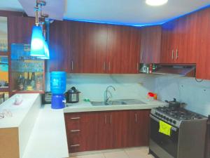 a kitchen with wooden cabinets and a sink and a stove at Villa Meyling, Tu Hogar en la Playa Crucita! in Crucita