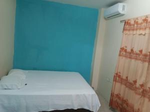 a bedroom with a white bed and a blue wall at Villa Meyling, Tu Hogar en la Playa Crucita! in Crucita