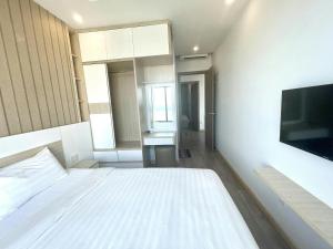 - une chambre avec un lit blanc et une télévision à écran plat dans l'établissement Mường Thanh Oceanus Nha Trang, à Nha Trang