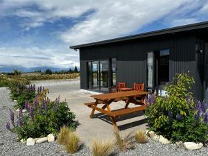 a house with a picnic table and a bench in front of it at GH Twizel Holiday Cottage in Twizel