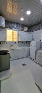 una cocina con armarios blancos y electrodomésticos blancos en إعمار الشرفةللشقق المفروشه en Najrán