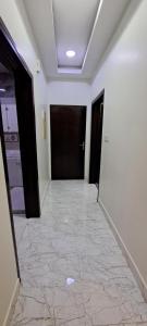 a hallway with black doors and a tile floor at إعمار الشرفةللشقق المفروشه in Najran