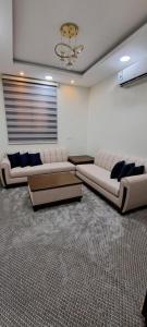 a living room with couches and a chandelier at إعمار الشرفةللشقق المفروشه in Najran