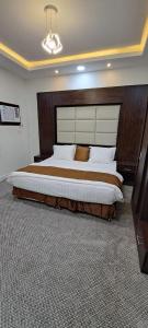 a bedroom with a large bed with a large headboard at إعمار الشرفةللشقق المفروشه in Najran