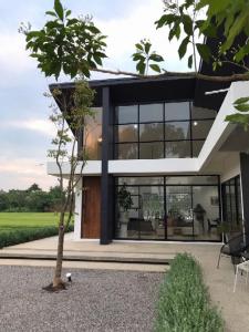 una casa con ventanas negras y un árbol en THE OAK’S en Chiang Rai