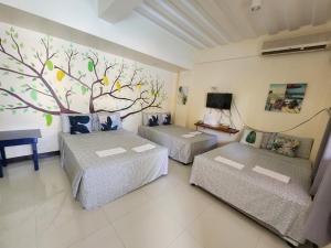 two beds in a room with a tree mural on the wall at Harang Hotel Mactan Lapulapu City Cebu Philippines in Maribago