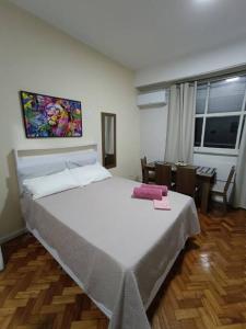 um quarto com uma grande cama branca e uma mesa em Lindo Loft na Cinelândia no Rio de Janeiro