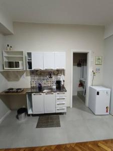 a kitchen with white cabinets and a white refrigerator at Lindo Loft na Cinelândia in Rio de Janeiro