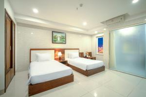 een hotelkamer met twee bedden en een groot raam bij Emerald Boutique Hotel DaNang in Da Nang