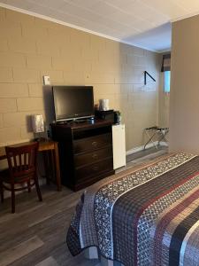 a hotel room with a bed and a flat screen tv at Pine Grove Motel in Sault Ste. Marie