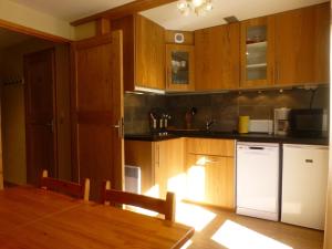 cocina con armarios de madera y nevera blanca en Appartement Peisey-Vallandry, 2 pièces, 6 personnes - FR-1-757-83, en Landry
