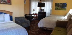 ein Hotelzimmer mit 2 Betten, einem Stuhl und einem Schreibtisch in der Unterkunft Pine Grove Motel in Sault Ste. Marie