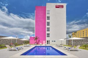 un hôtel avec une piscine et un bâtiment rose dans l'établissement City Express Suites by Marriott Silao Aeropuerto, à Silao