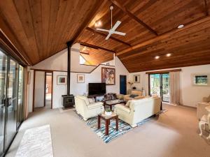 una sala de estar con muebles blancos y techo de madera. en Lake Russell Retreat, en Emerald Beach