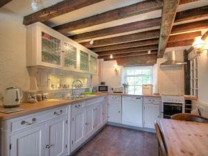 a large kitchen with white cabinets and a wooden table at Henfaes Isaf in Cynwyd