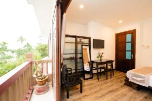 Habitación con balcón, cama y escritorio. en B'Lan Riverside Villa, en Hoi An