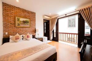 1 dormitorio con 1 cama grande y pared de ladrillo en B'Lan Riverside Villa, en Hoi An