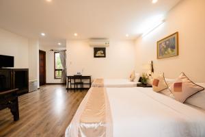 una habitación de hotel con 2 camas y un piano en B'Lan Riverside Villa, en Hoi An