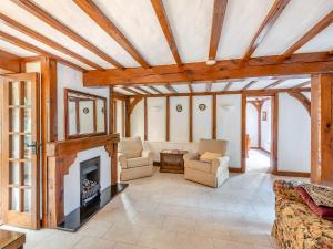 una sala de estar con chimenea y techos de madera. en Gardeners Cottage, en Kelvedon Hatch