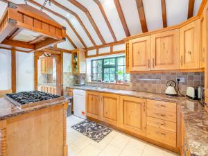 cocina con armarios de madera y fogones en Gardeners Cottage, en Kelvedon Hatch