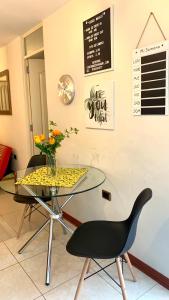 a glass table with two chairs and a vase of flowers at Cusco Magico 7 - Minidepartamento Las Torres Kayser in Cusco