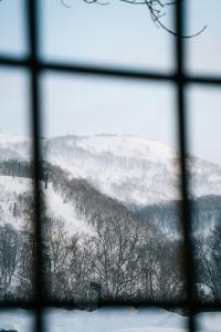 a view of a snow covered hill from a window at Alpenglow Lodges Ginkei in Niseko