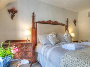 a bedroom with a bed with a wooden headboard and a dresser at Henfaes Isaf in Cynwyd