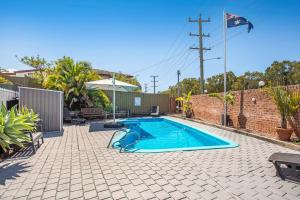 a swimming pool in a yard with a brick wall at Lake Macquarie Motor Inn in Belmont