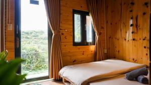 - une chambre avec un lit et une grande fenêtre dans l'établissement Dalat 1AM, à Xuan An