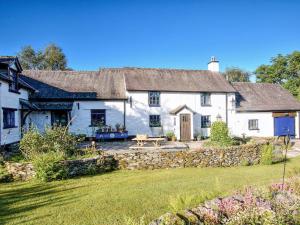 a white cottage with a stone wall at Henfaes Isaf in Cynwyd