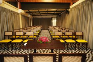 Misty Queen By Dimora Hotels في Kakkadampoyil: غرفة بها صفوف من الكراسي وطاولة وزهور