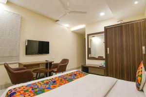 a room with a bed and a desk and a tv at FabHotel Prism Grand in Zirakpur