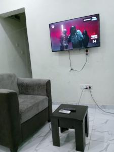 a living room with a couch and a tv on the wall at F&B Service Apartment in Abeokuta