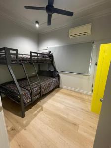 a room with two bunk beds and a ceiling fan at Banana Backpackers in Brisbane