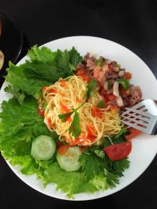 a white plate of food with spaghetti and lettuce at Be Them homestay in Hue