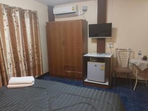 a room with a bed and a desk and a television at Patong Rose Guest House in Patong Beach
