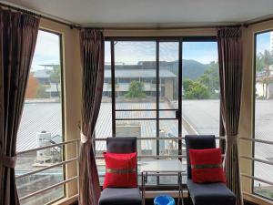 einen Balkon mit 2 Stühlen, einem Tisch und Fenstern in der Unterkunft Patong Rose Guest House in Patong Beach