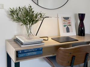 a desk with a vase of flowers and books at Stylish 2Bdrm in Trendy Area -Close to City & Beach in Perth