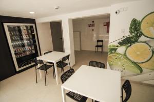 a room with white tables and chairs and a drink at Hostel Floridita Adults Only in Magaluf