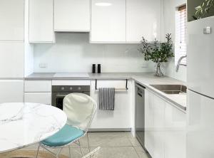 a white kitchen with a table and a blue chair at Stylish 2Bdrm in Trendy Area -Close to City & Beach in Perth