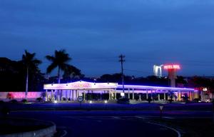 a lit up building with a neon sign at night at Hotel & Motel Le Baron in Pôrto Ferreira