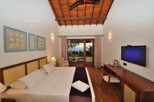 a room with a bed and a tv and a couch at Tantalize Beach in Hikkaduwa