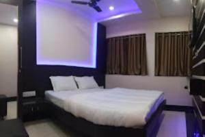 1 dormitorio con 1 cama blanca con luz morada en Hotel Raj Residency, Patna, en Patna