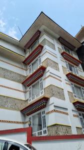 a tall building with red and white at Jain Group- Keepsa Residency & Spa, Gangtok in Gangtok