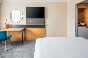 a hotel room with a bed and a desk and a mirror at Holiday Inn London - Gatwick Airport by IHG in Horley